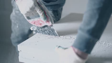 worker-in-gloves-finishes-sawing-big-white-gypsum-board