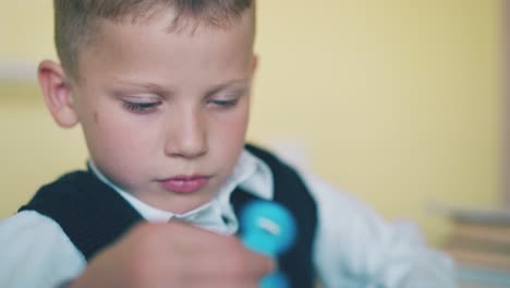 kid-plays-with-turning-spinner-resting-at-break-in-classroom