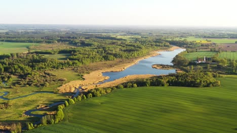 Scenic-drone-footage-of-a-river,-green-farm-fields-and-trees-in-Central-Europe