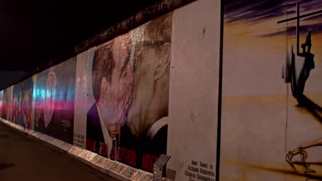 Establishing-side-shot-of-Fraternal-Kiss-graffiti-painting-in-Berlin-wall,-night