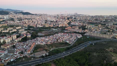 Malaga-cityscape-and-highway-traffic-during-sunset-at-Costa-del-Sol,-Andalusia,-Spain---Aerial