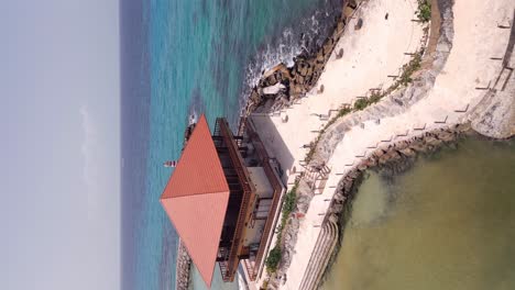 Meereswellen-Krachen-An-Der-Felsigen-Küste-Des-Strandes-Mit-Restaurant-In-La-Romana,-Dominikanische-Republik