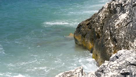 Close-up-on-foamy-waves-crashing-against-a-rocky-cliff-on-Corfu-Island