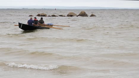 Crew-of-three-paddle-and-get-turned-around-by-waves-in-currach-boat