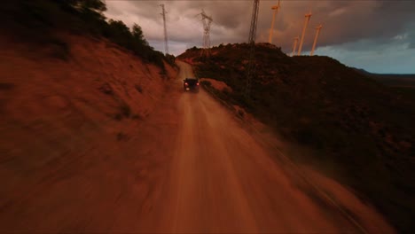 FPV-aerial-drone-tracking-a-Hummer-driving-along-a-dirt-road-at-sunset