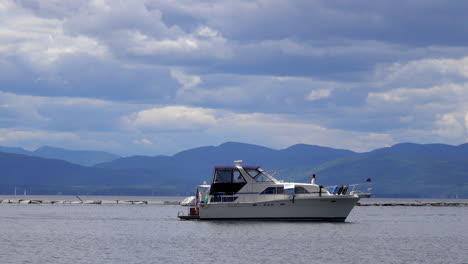 Un-Barco-Crucero-De-Cabina-En-El-Lago-Champlain-Con-Montañas-Al-Fondo