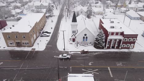 Snow-covered-church-building-in-downtown-of-small-American-town,-aerial-view