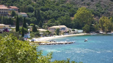 Blick-Auf-Einen-Strand-Am-Blauen-Meer-Auf-Der-Insel-Korfu,-Mit-Gebäuden-Und-Wohnungen-Im-Hintergrund
