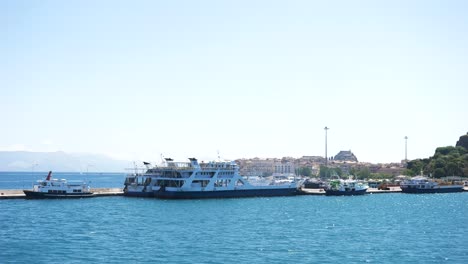 Vista-Desde-Un-Ferry-De-Barcos-Y-Ferries-Atracados-En-El-Puerto-De-La-Isla-De-Corfú.