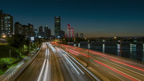 Timelapse-of-Night-Traffic-on-Olympic-Daero-Expressway-with-Yeouido-FInancial-District-Buildings-and-63-Building-Tower-View,-Subway-Train-Crossing-Han-River---panning-hyperlapse