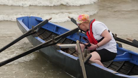 Solo-female-bails-water-out-of-traditional-wooden-irish-racing-currach-before-racing