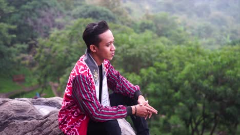 A-male-sitting-on-the-edge-of-rock-cliff-while-enjoying-the-beautiful-mountain-scenery