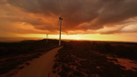 FPV-drone-arcing-around-a-Hummer-at-sunset-at-a-wind-turbine-farm
