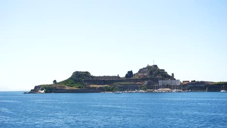 Blick-Auf-Die-Insel-Korfu-Von-Einer-Segelfähre-Aus,-Mit-Gebäuden-Und-Einem-Kreuz-Darauf