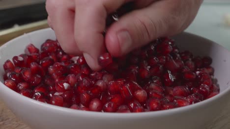 Medium-close-up-of-a-mans-hand-in-a-bowl-of-pomegranate