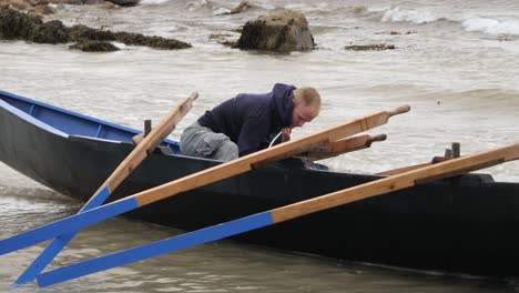 Solo-man-bails-out-currach-traditional-irish-boat-in-the-gentle-surf