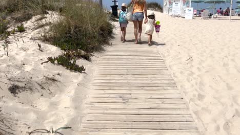 Mamá-Con-Niños-Camina-Y-Juega-En-La-Playa-De-Arena-Junto-Al-Mar