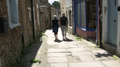 A-couple-wonder-along-a-narrow-and-very-old-paved-street-in-a-rural-town-in-England