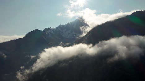 Aerial-slider-reveal-shot-of-jagged-mountain-peak-shrouded-in-cloud
