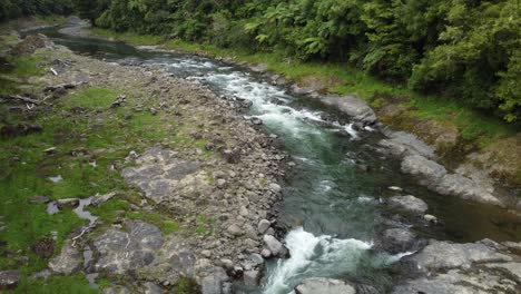 Clear-pristine-mountain-river-flowing-through-forest-over-rapids-aerial-view