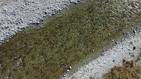 Aerial-view-above-clear-river-flowing-over-gravel-bed