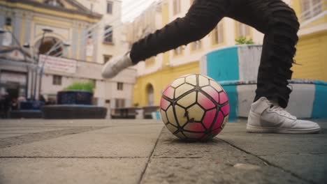 Person-with-Nike-shoes-kick-football-in-streets-of-Naples,-celebrating-concept