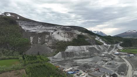 Rising-aerial-view-of-Limestone-and-quarry-mining-site-for-between-Molde-and-Kristiansund-in-Norway---Aerial-showing-heavy-machinery-and-equipment-at-job-site-and-damaged-mountain-in-background