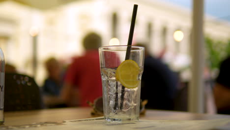 Focus-on-a-transparent-glass-of-sparkling-water-with-lemon-and-a-black-straw