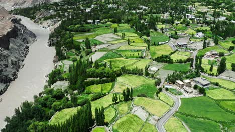 Aerial-panorama-view-of-Leh-village-during-monsoon-season-when-river-full-of-water-flowing,-greenery-nearby-surrounding