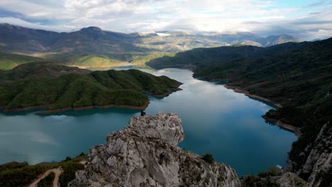 Aerial-of-man-sitting-on-a-rock-at-Bovilla-Lake-near-Tirana-in-Albania
