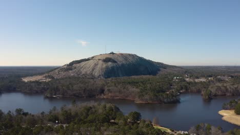 Wide-aerial-drone-shot-of-Stone-Mountain-in-Stone-Mountain-Park-slowing-flying-away-while-facing-the-Confederate-mural-on-the-North-side-of-the-rock-face