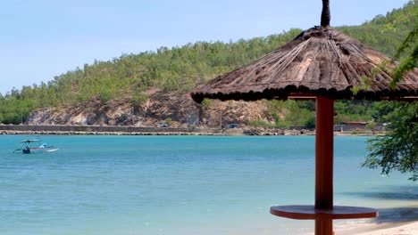 Malerische-Aussicht-Auf-Einen-Picknicktisch-Mit-Strohdach-Am-Strand-Mit-Türkisfarbenem-Meer-In-Dili,-Timor-Leste,-Südostasien