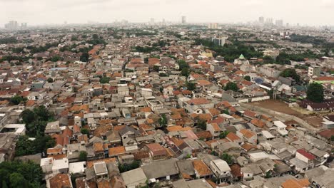 Aerial-backwards-flight-over-crowded-slum-in-Jakarta-City-with-many-destroyed-old-houses,-Indonesia