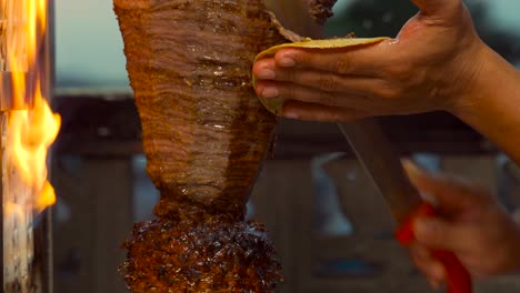 Mexican-latin-taquero-cooker-cut-grill-meat-from-trompo-de-tacos-de-carne-asada-pastor-taco-flames-juicy-slice