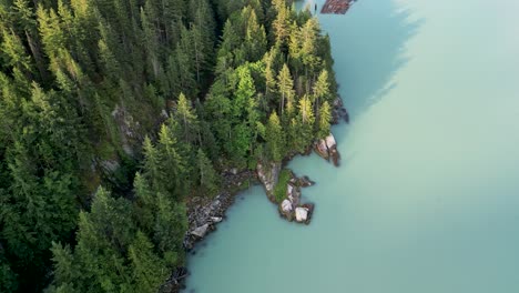 Aerial-pan-of-coastal-pine-trees-and-water,-Squamish,-BC,-Canada