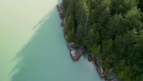 Aerial-topdown-pan-of-Howe-Sound-ocean-coastline-and-trees-Stawamus-Chief-reveal,-Squamish,-BC,-Canada