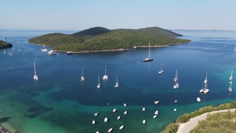 Boats-sail-near-Syvota-Coast-and-Green-Island-in-Ionian-Sea-at-Epirus,-Greece---Aerial