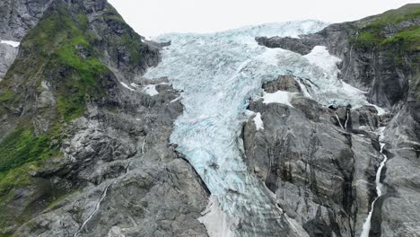 Boyabreen-glacier-full-close-up-detail-view-with-melting-glacier-water-stream-flowing-down-on-right-side---Aerial-of-Fjaerland-part-of-the-Jostedal-Glacier-Norway---60-FPS