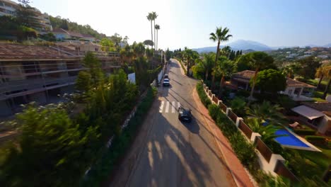 FPV-aerial-drone-following-a-Porsche-driving-along-a-scenic-road-in-Marbella,-Spain