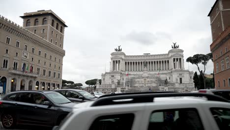 A-slow-motion-pan-overlooking-the-Piazza-Venezia-with-the-Victor-Emmanuel-II-National-Monument-in-the-background-as-traffic-passes-by,-Rome,-Italy