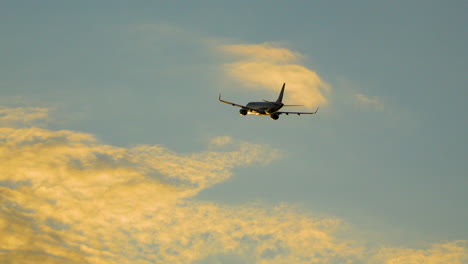 Jet-Airplane-Climbs-Into-Sunset-Sky-with-Orange-Clouds