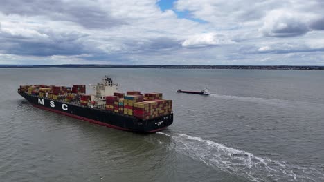 Panning-drone-aerial-MSC-Madeleine-container-ship-sailing-up-river-Thames-Estuary-UK