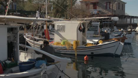 Zwei-Griechische-Fischer-Reparieren-Netze-An-Bord-Ihrer-Boote-Im-Hafen
