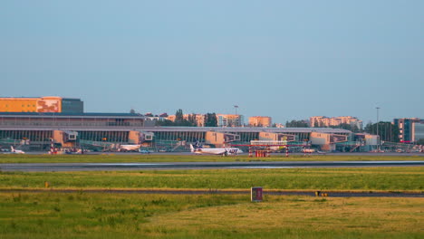 Warsaw-Chopin-Airport-Airfield-At-Sunset---Passenger-Airplane-Moving-Along-the-Aerodrome-Towards-Runway---wide-low-angle-static