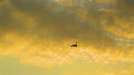 Passenger-Jet-Airplane-in-Flight-After-Takeoff-Ascends-Into-Colorful-Sunset-Sky-With-Orange-Clouds