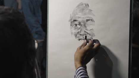 slow-motion-shot-of-a-street-artist-drawing-a-portrait-of-an-older-man-using-charcoal