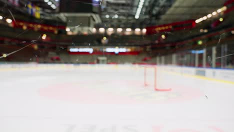 Out-of-focus-hockey-arena-with-in-focus-plexiglass-in-foreground