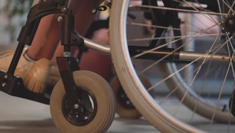 Beine-Einer-Patientin-Mit-Behinderung,-Die-Sich-Im-Rollstuhl-Im-Zimmer-Bewegt