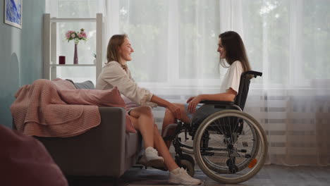 Supportive-woman-holds-hands-of-girlfriend-in-wheelchair
