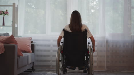 Brunette-woman-moves-wheelchair-closer-to-bright-window